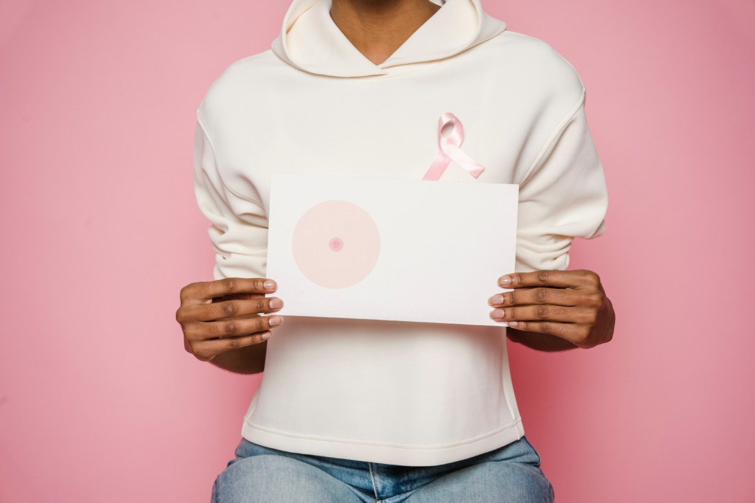 Photo d'une femme tenant l'image d'un sein manquant et portant le ruban rose, symbole d'Octobre Rose